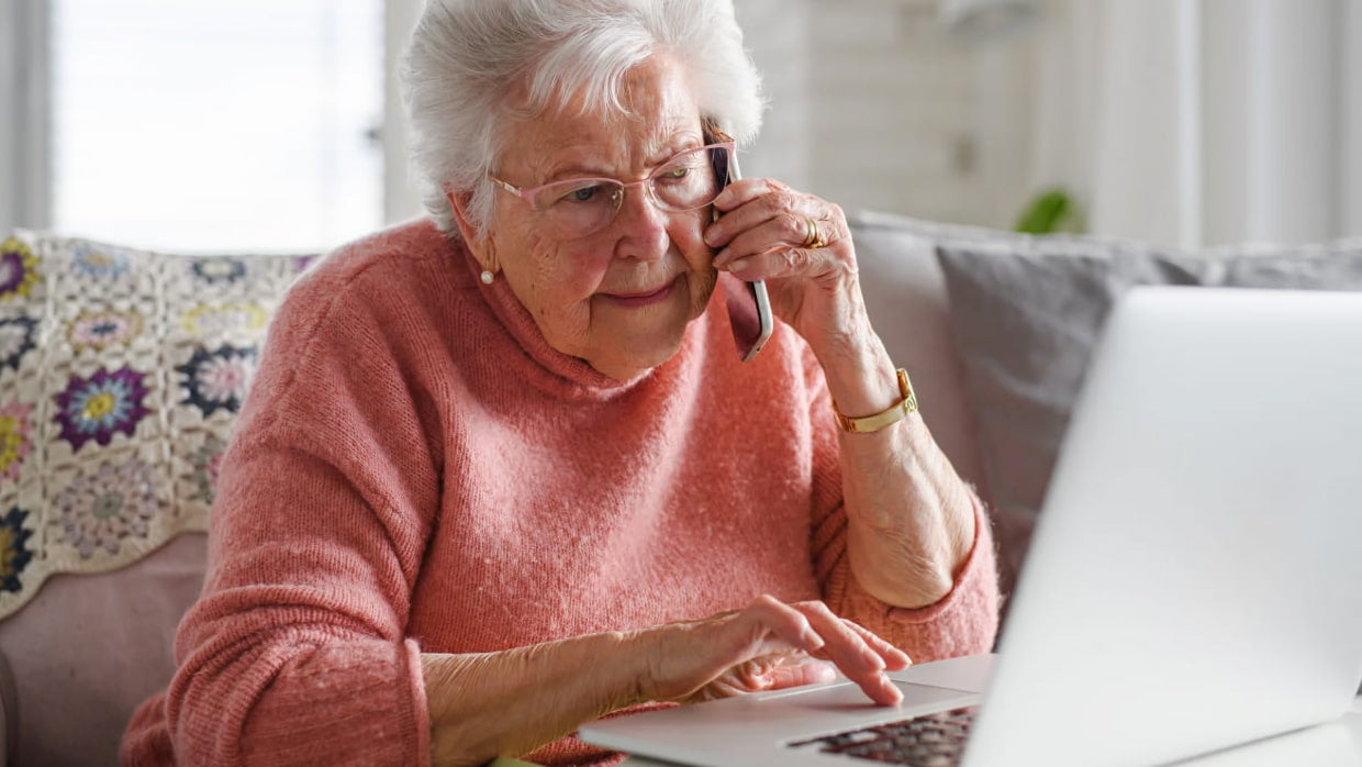 senior woman on phone using laptop