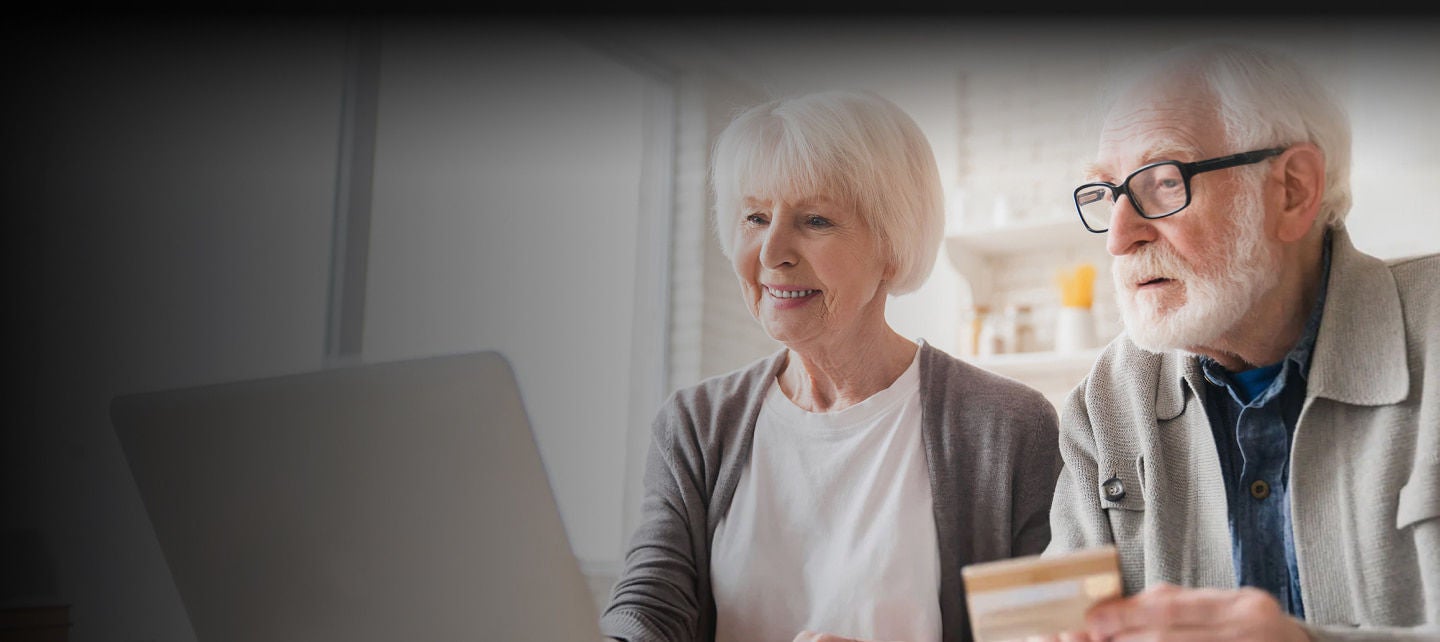 senior couple on laptop paying with card