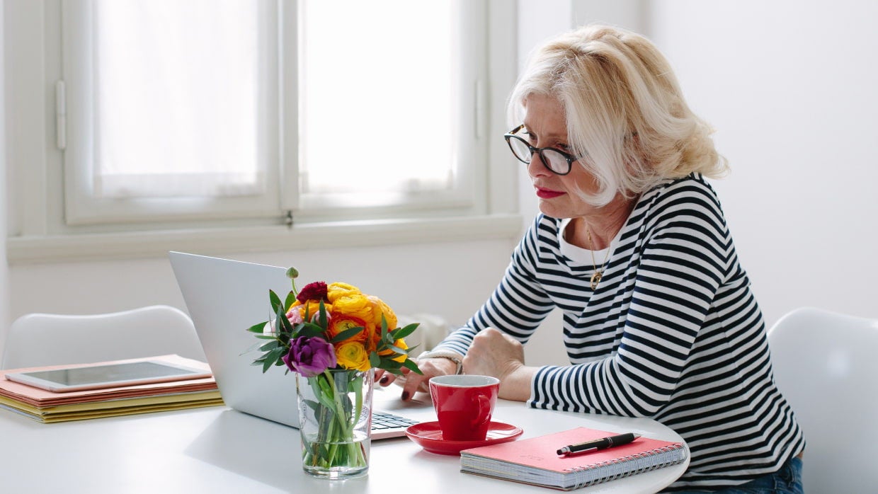 senior woman working on laptop at table