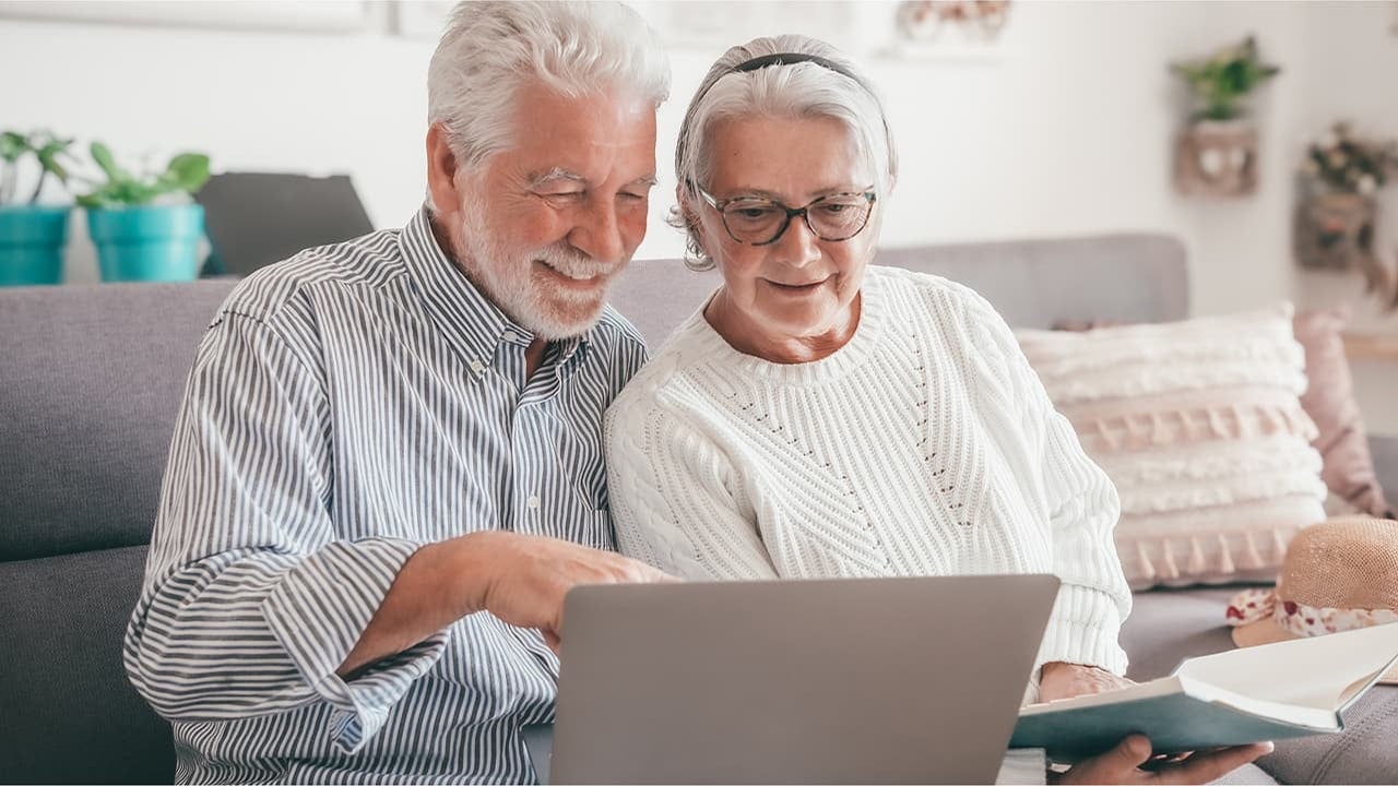 senior couple using devices at cafe