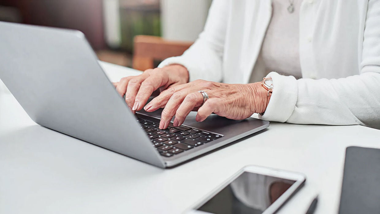mature hands typing on laptop