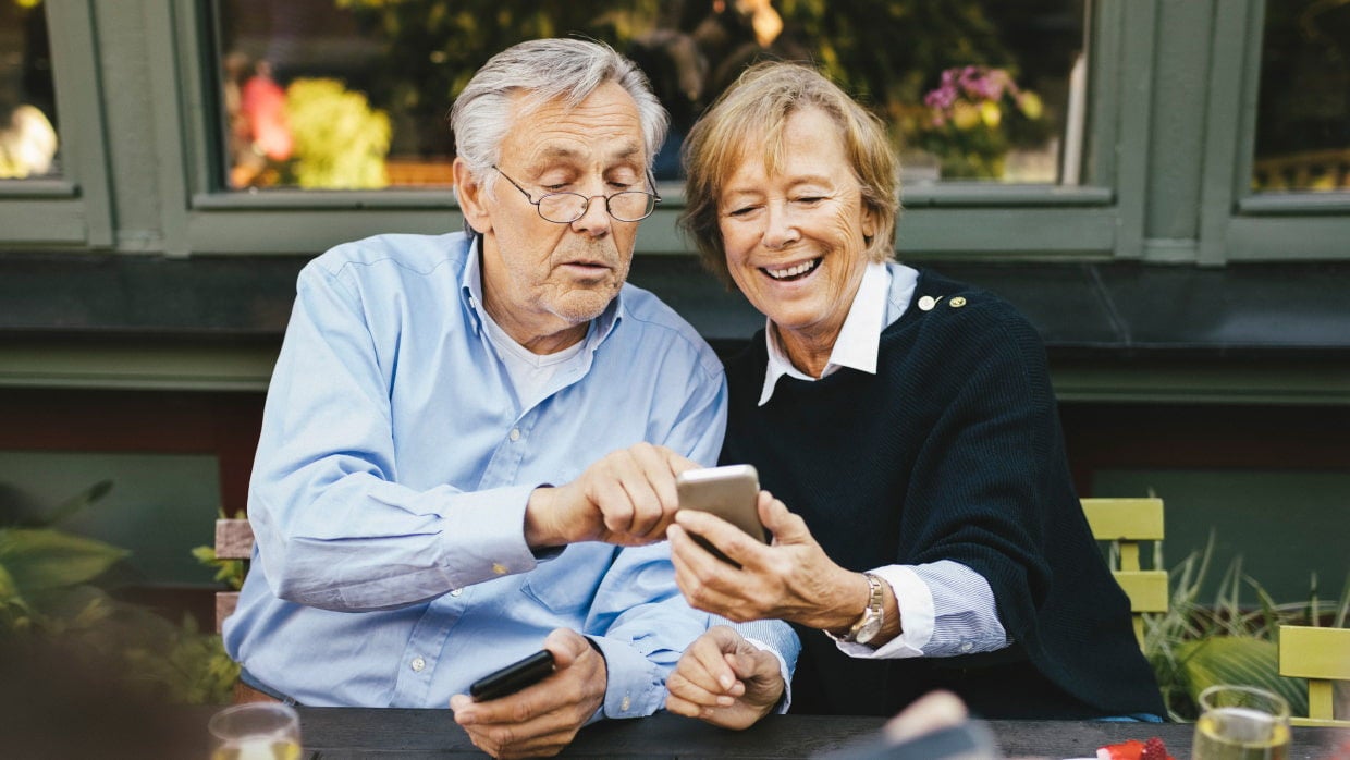 senior couple using devices at cafe